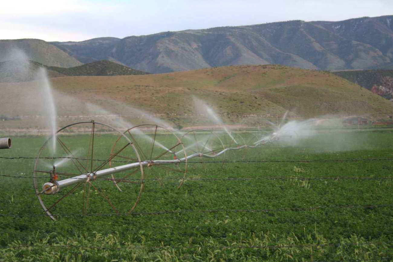 Pivot irrigation running on a green field below the mountains in Sevier County